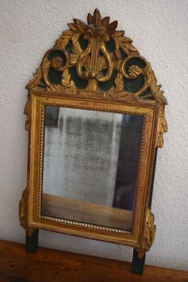 a mirror sitting on top of a wooden table next to a wall
