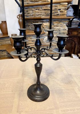 a black candelab with five candles on it on a table