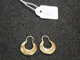 a pair of gold earrings on a black surface with a price tag