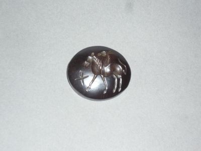 un bouton en métal sur lequel figure l'image d'un homme à dos de chameau