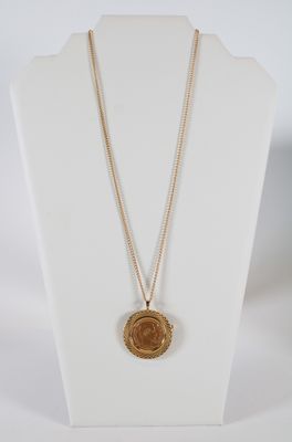 a gold necklace with a coin on a white mannequin