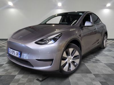 the silver tesla model y is parked in a room with checkered flooring