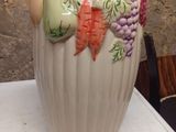 a white vase with a bunch of fruits on it