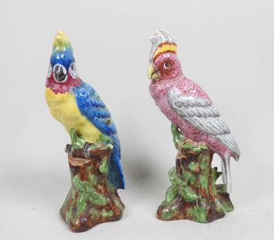 deux figurines représentant des oiseaux colorés perchés sur une souche d'arbre