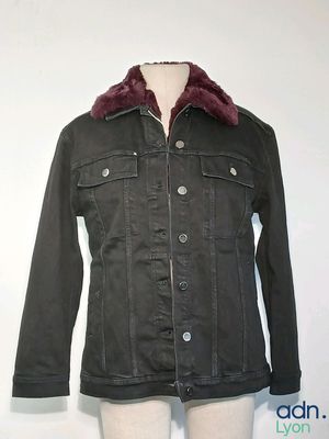 La veste est noire et dotée d'un col en fourrure.