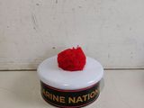 a small white container with a red pom pom on top of it