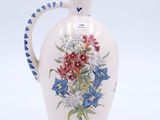 un vase blanc avec une anse bleue et des fleurs peintes dessus