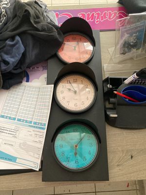 trois horloges posées sur une table à côté d'une pile de papiers