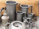 a lot of silver vases and pitchers on a table