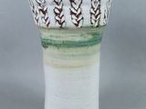 un vase blanc orné de motifs verts et marron