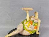 figurine représentant une femme allongée sur le ventre, un frisbee à la main