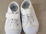 pair of white baby shoes with white laces on a couch