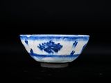 blue and white bowl with flowers on it on a black surface
