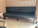 a black leather bench in a room with a wooden wall behind it