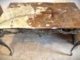 une table en marbre avec un piètement en métal, posée sur un sol carrelé