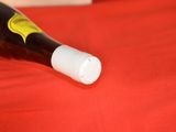 a bottle of wine sitting on a bed with a red sheet