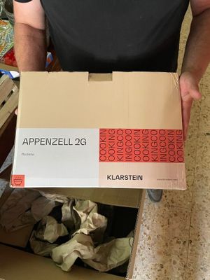 Quelqu'un tient une boîte sur laquelle figure la photo d'un homme en chemise noire.
