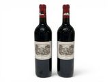 deux bouteilles de vin rouge posées l'une à côté de l'autre sur une surface blanche