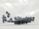 un sachet de perles bleues et noires posé sur une surface blanche