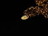 a close up of a gold chain with a coin on it