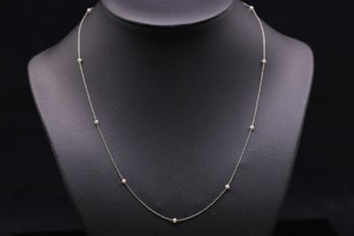 a necklace with pearls on a mannequin with a black background