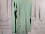 green sweater on a mannequin stand in front of a white wall