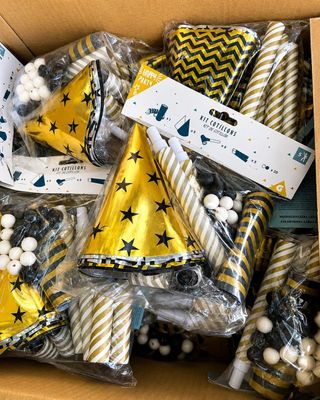 des chapeaux de fête jaunes et noirs et des décorations dans une boîte en carton