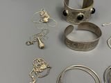many different types of silver jewelry on a table