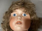 a close up of a doll with blue eyes and brown hair