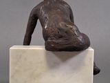 statue of a man sitting on a marble block with his back to the camera
