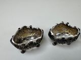 two silver dishes with black and white designs on them