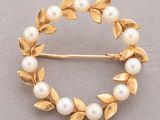 a close up of a brooch with pearls and leaves