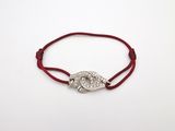 un bracelet en fil rouge orné d'un pendentif représentant l'œil maléfique