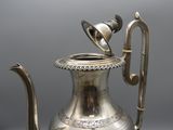 silver plated coffee pot with a handle and handle on a table