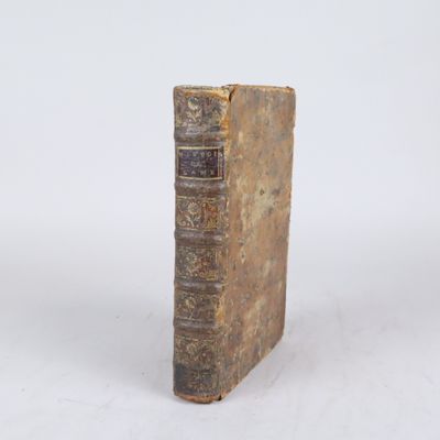 un vieux livre posé sur une table à côté d'un mur blanc