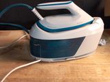 a white and blue steam iron sitting on a wooden table