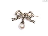 a close up of a pearl and diamond bow broochle