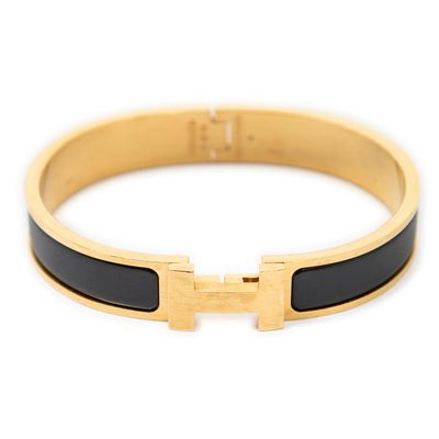 a close up of a gold bracelet with a black enamel band