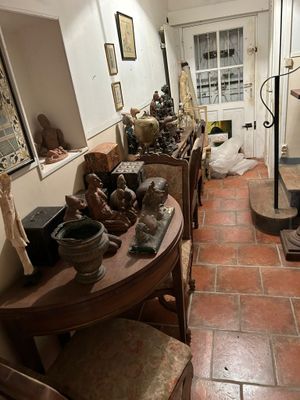 un homme debout dans une pièce où il y a beaucoup d'objets sur la table