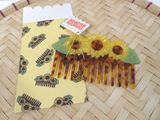 a yellow comb with yellow flowers on it sitting on a basket