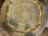 someone standing next to a table with a gold plate on top of it