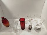 de nombreux verres à vin posés sur une table, avec un vase rouge