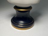 a white vase with a black base on a white table
