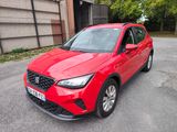 une voiture rouge garée sur le bord de la route, devant un immeuble