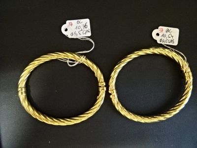 deux bracelets en fil métallique doré posés sur une surface noire