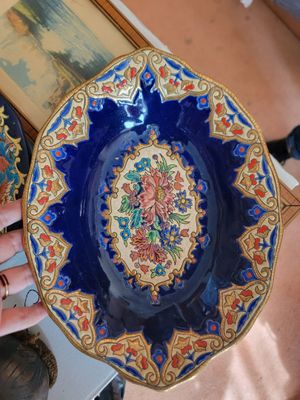 a person holding a blue and gold plate with a picture on it