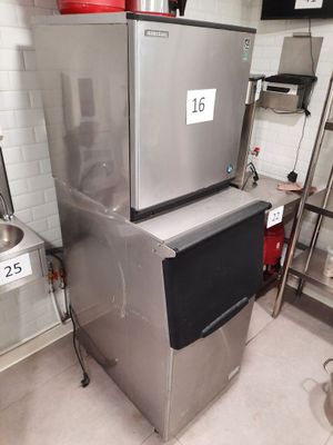 a silver refrigerator in a kitchen with a red bucket on top of it