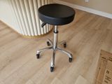 a black stool sitting on top of a wooden floor next to a radiator