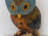 une statue de chouette posée sur une étagère blanche