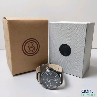 une photo montrant une montre posée à côté d'une boîte sur une table